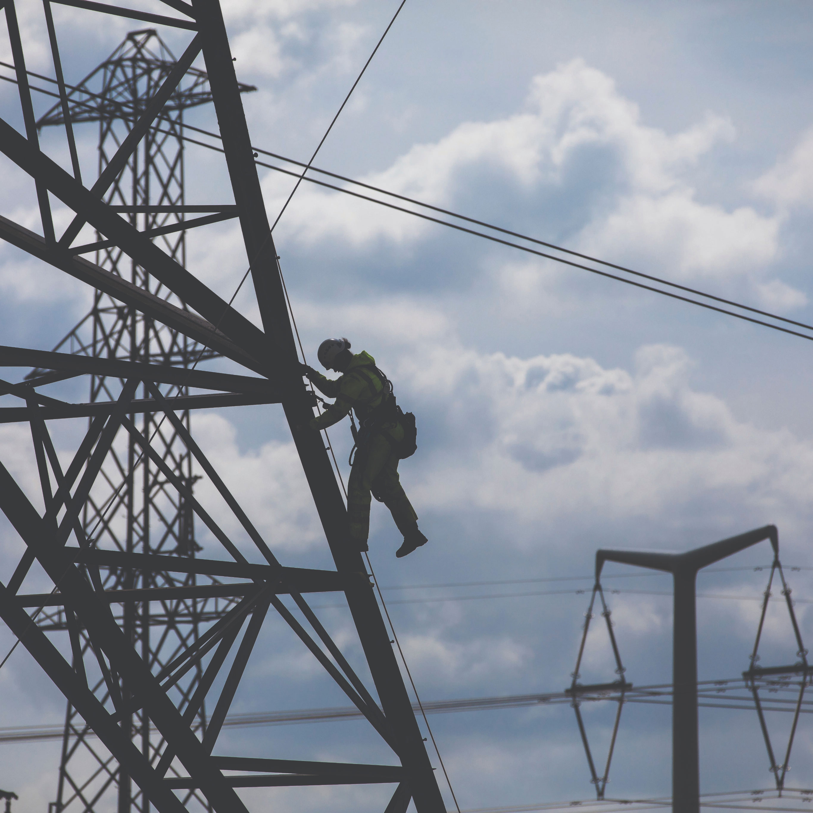 Silhouette of modern electrical transmission tower against a cloudy sky